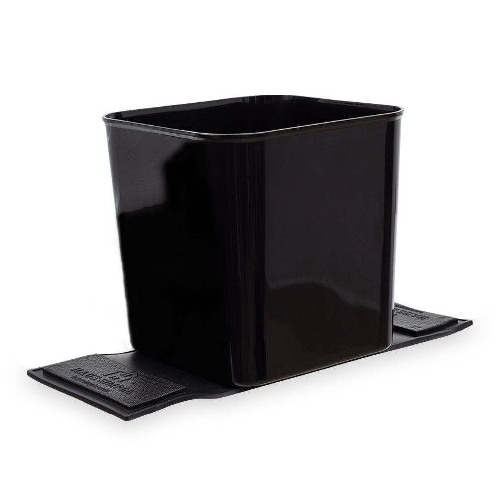 A large black car trash can with stability flaps, designed to be placed on a fabric floor mat in a vehicle.